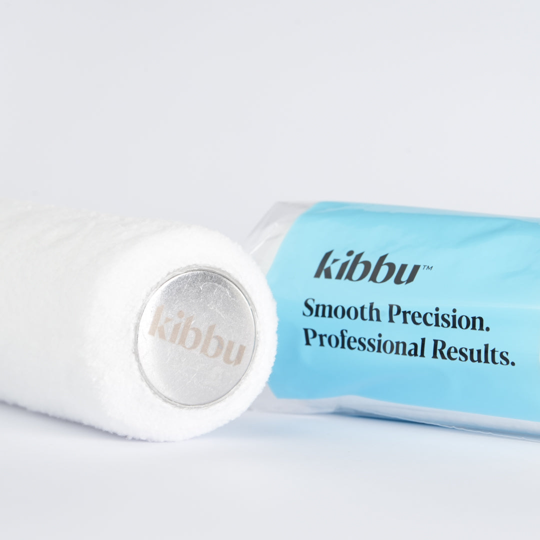 Close-up of Kibbu 270mm microfibre roller sleeve end showing embossed logo with blue packaging behind
